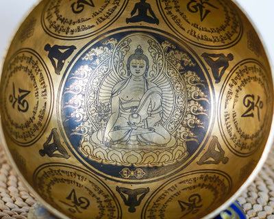 Medicine Buddha singing bowl shown upright with a wooden handled mallet and decorative engraving