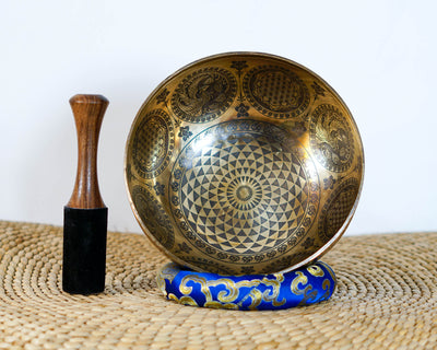 Cosmos engraved singing bowl displayed upright with a wooden mallet and blue cushion, showcasing its detailed geometric interior.