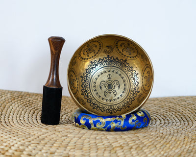 Turtle inspired engraved singing bowl displayed upright with a wooden mallet and blue cushion, showing the detailed interior artwork.