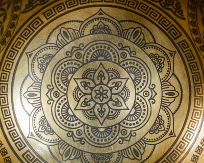 Close up of the golden singing bowl interior featuring an intricate floral mandala engraving with symmetrical geometric patterns.
