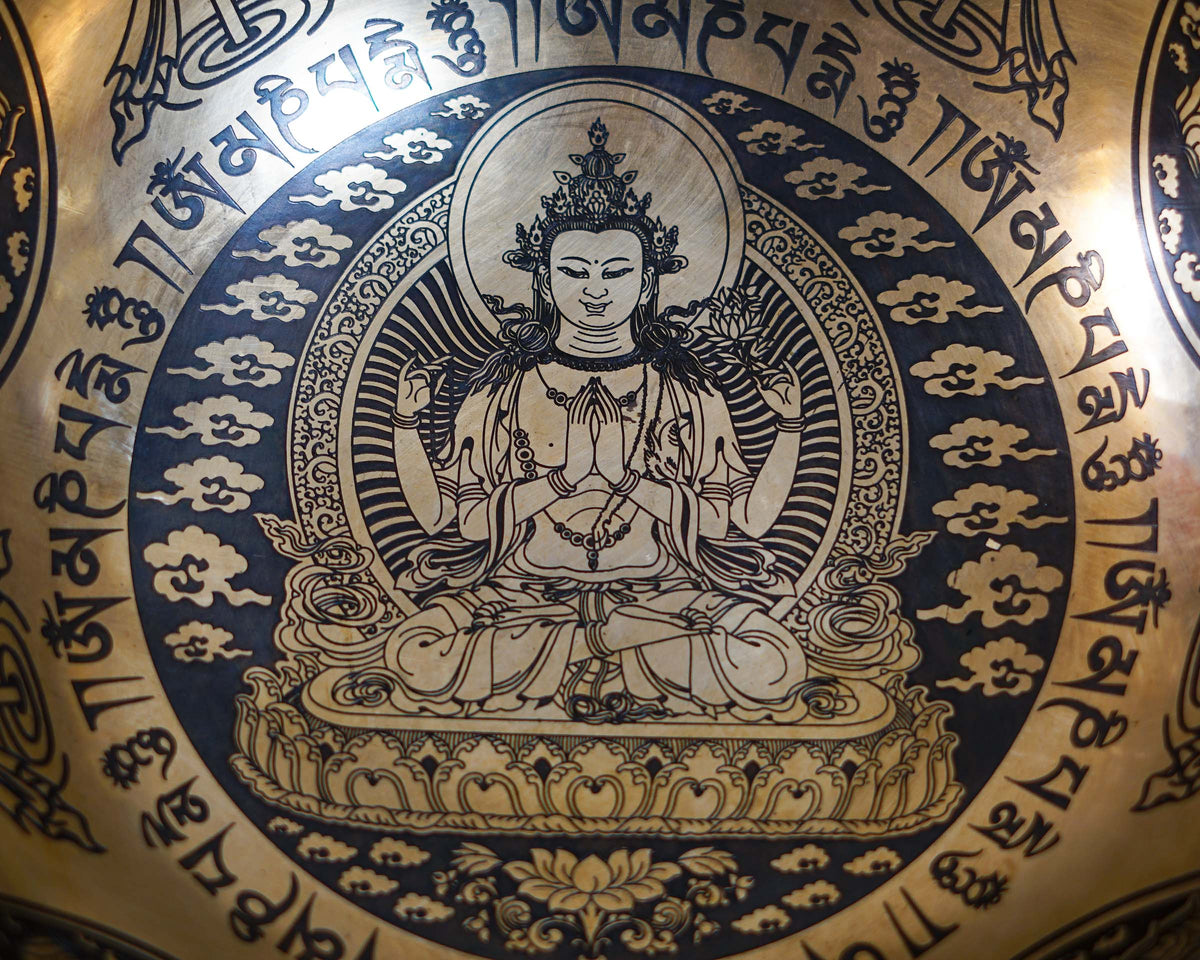 Close up of Chengresi Bodhisattva of Compassion engraved inside a golden bronze tone singing bowl with Tibetan mantras