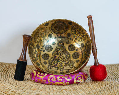 Golden Chakra Yogini singing bowl with engraved exterior motifs displayed on a purple brocade cushion