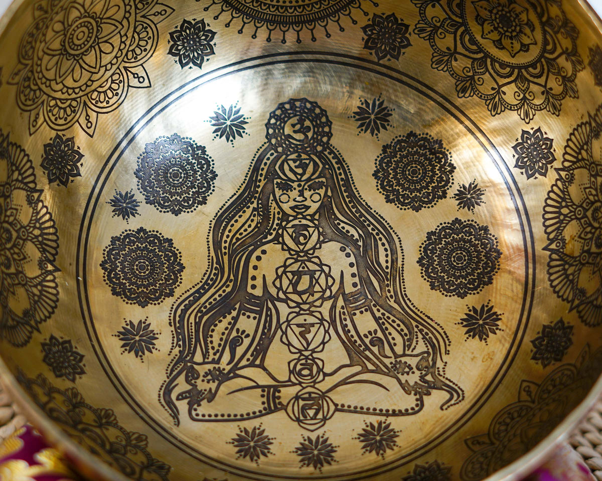 Close up of Chakra Yogini engraving with seven chakra symbols and floral mandala patterns inside a golden singing bowl