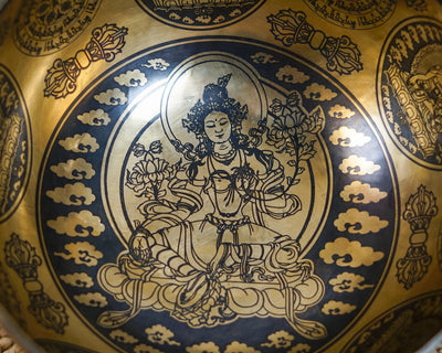 Close up of Green Tara engraving with lotus flowers and decorative cloud motifs inside a golden bronze tone singing bowl