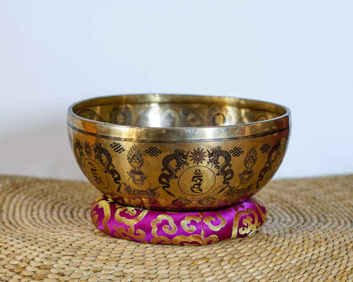Green Tara singing bowl showing engraved dragons, auspicious knots, and traditional Himalayan decorative motifs on the exterior
