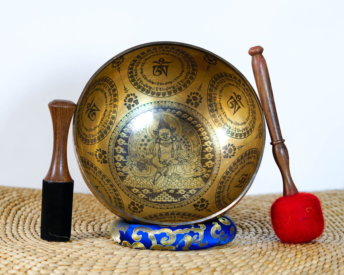 Zambala engraved singing bowl shown upright with a wooden mallet and blue cushion, highlighting the intricate interior artwork.