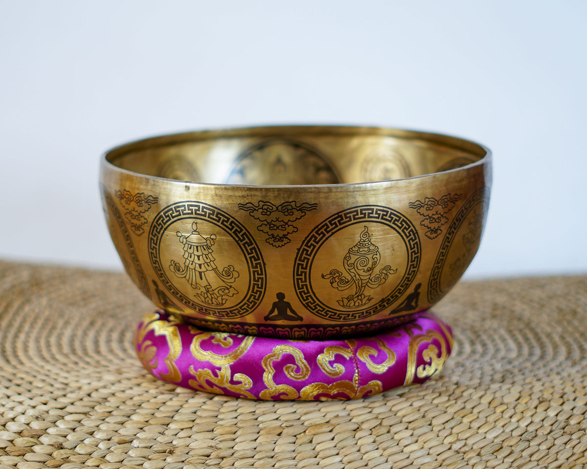 Golden Buddha Mandala singing bowl showing circular Buddhist symbols and decorative engravings on the exterior