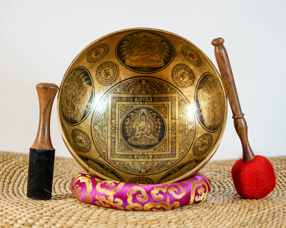 Close up of Buddha seated on a lotus throne inside an engraved geometric mandala on a golden bronze tone singing bowl