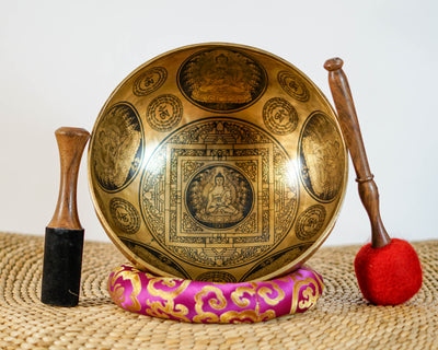 Close up of Buddha seated on a lotus throne inside an engraved geometric mandala on a golden bronze tone singing bowl