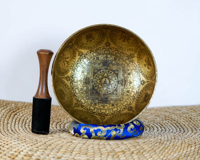 Kalchakra Yogini Singing Bowl displayed upright with a wooden mallet and blue cushion, showing the central mandala design.