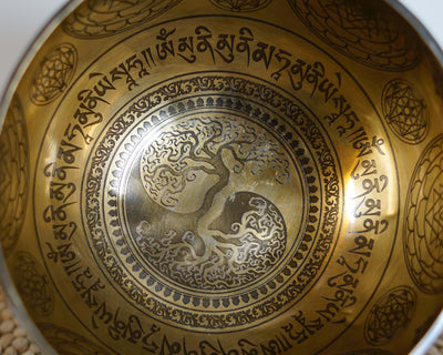 Close up of the Tree of Life engraving surrounded by Tibetan mantras and geometric patterns inside a golden bronze tone singing bowl