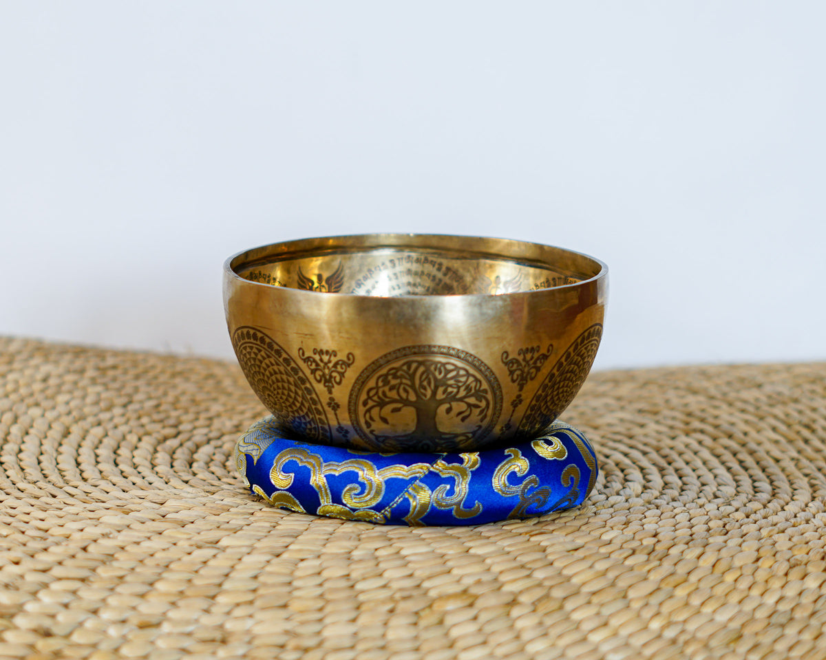 Engraved Kal Mandala singing bowl shown upright with a wooden mallet and decorative cushion.
