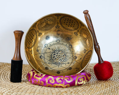 Universe singing bowl shown upright with a wooden mallet and pink cushion, featuring detailed celestial engravings inside.