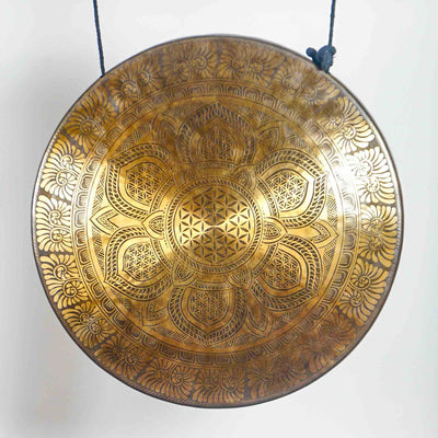 Front view of a circular antique-bronze gong displaying detailed lotus petals, sacred geometry and floral engraved borders.