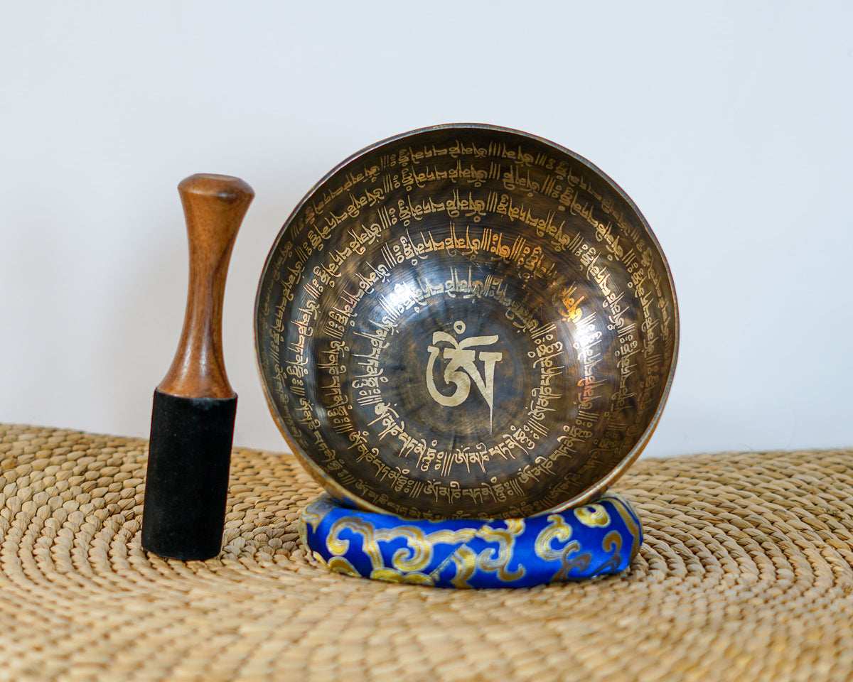 Detail of the sacred Om symbol and circular mantra engravings inside a traditional Himalayan inspired singing bowl.