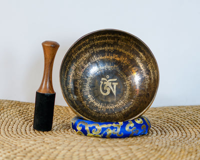 Detail of the sacred Om symbol and circular mantra engravings inside a traditional Himalayan inspired singing bowl.