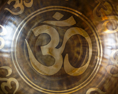 Close up of the sacred Om symbol engraved inside a dark bronze and gold Hindu singing bowl.