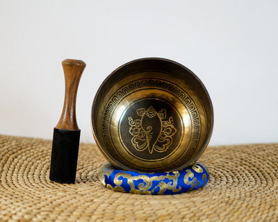 Conch shell engraved Tibetan singing bowl with dark bronze exterior and gold Tibetan script detailing.