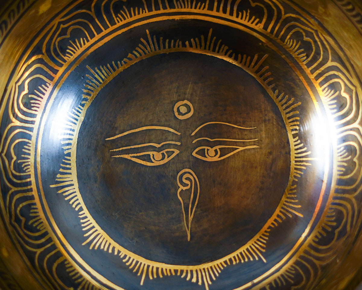 Close up of the golden Buddha Eyes engraving surrounded by decorative circular patterns inside a Himalayan inspired singing bowl.