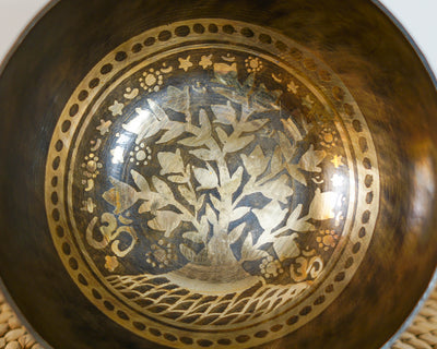 Close up of the Tree of Life engraving inside a dark antique gold singing bowl with golden branches and leaves.