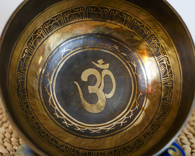 Close up of a golden Om symbol engraved inside a dark circular center of a Hindu singing bowl.