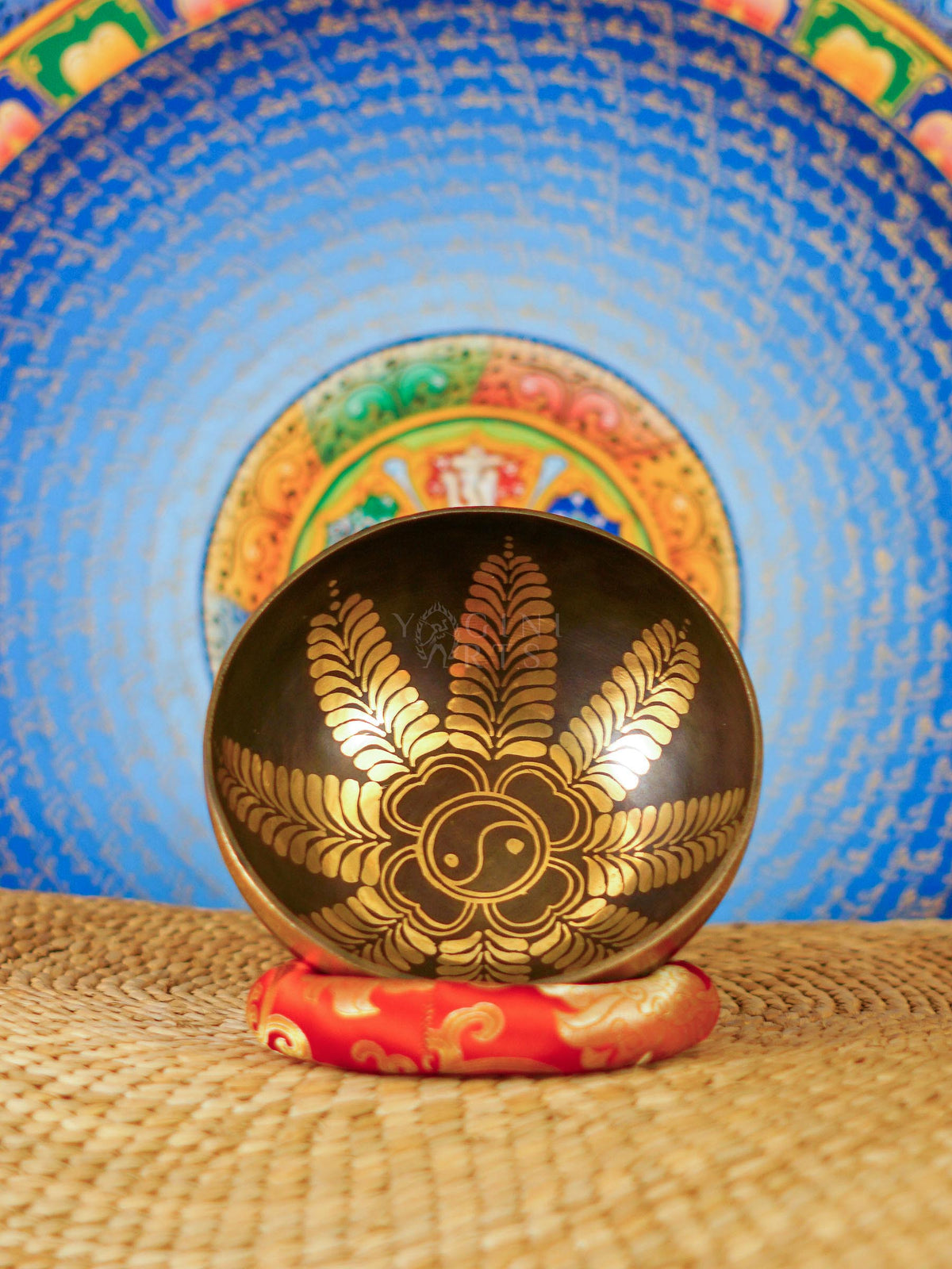 Handcrafted Yin Yang singing bowl from Nepal with gold floral engraving, dark bronze finish, decorative cushion and wooden striker.