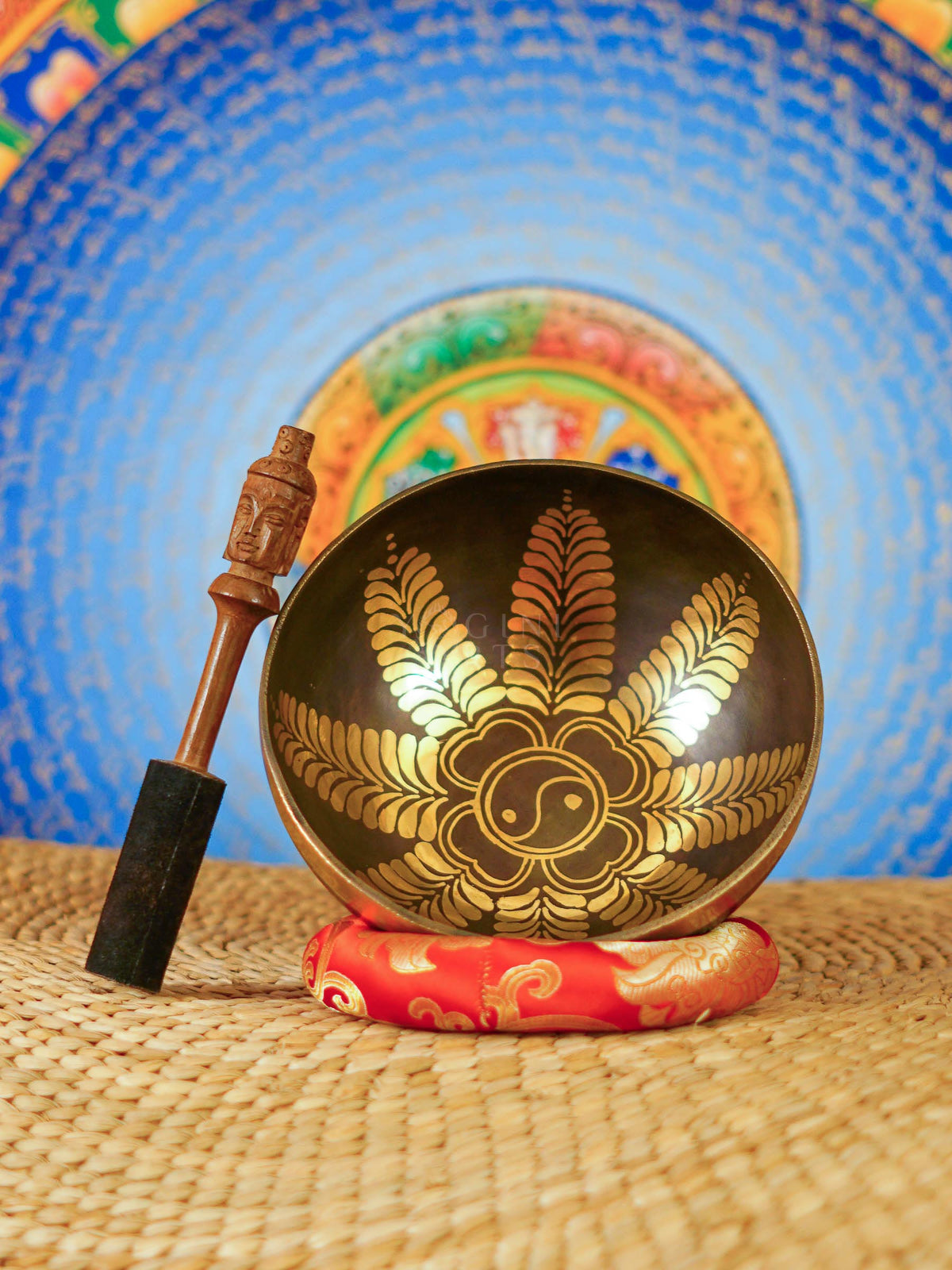 Handcrafted Yin Yang singing bowl from Nepal with gold floral engraving, dark bronze finish, decorative cushion and wooden striker.