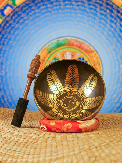 Handcrafted Yin Yang singing bowl from Nepal with gold floral engraving, dark bronze finish, decorative cushion and wooden striker.