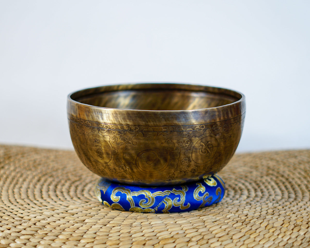 Cosmos engraved Tibetan singing bowl with ornate exterior motifs and an antique bronze and gold finish.