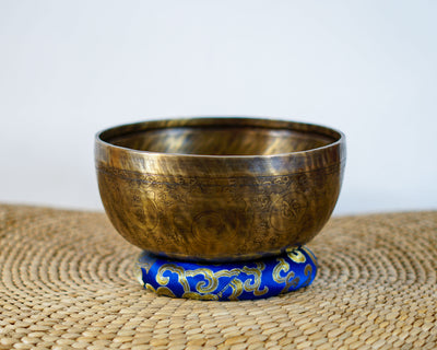 Cosmos engraved Tibetan singing bowl with ornate exterior motifs and an antique bronze and gold finish.