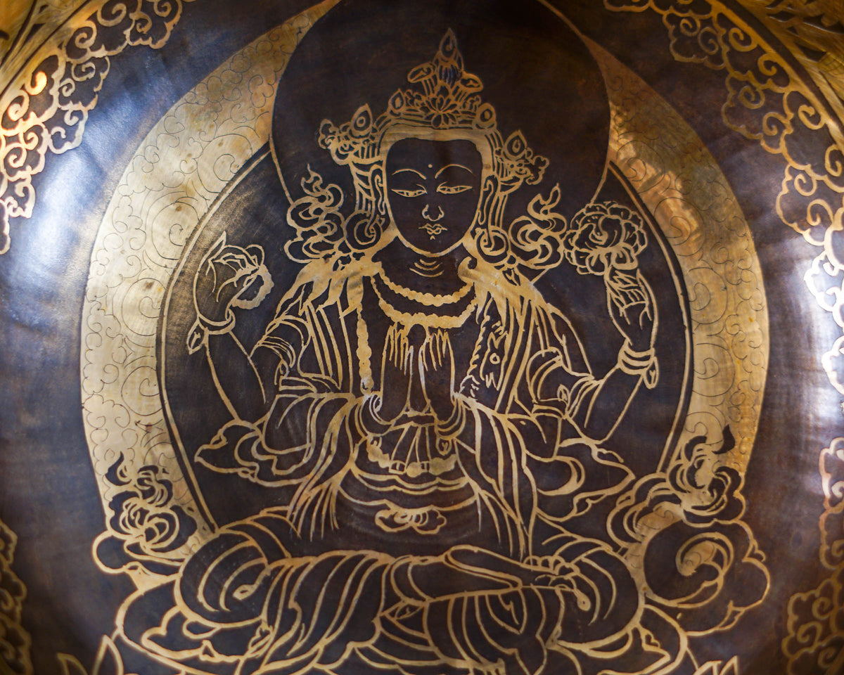 Close up of Chengresi engraved inside a golden Tibetan singing bowl with intricate floral borders and dark bronze detailing.