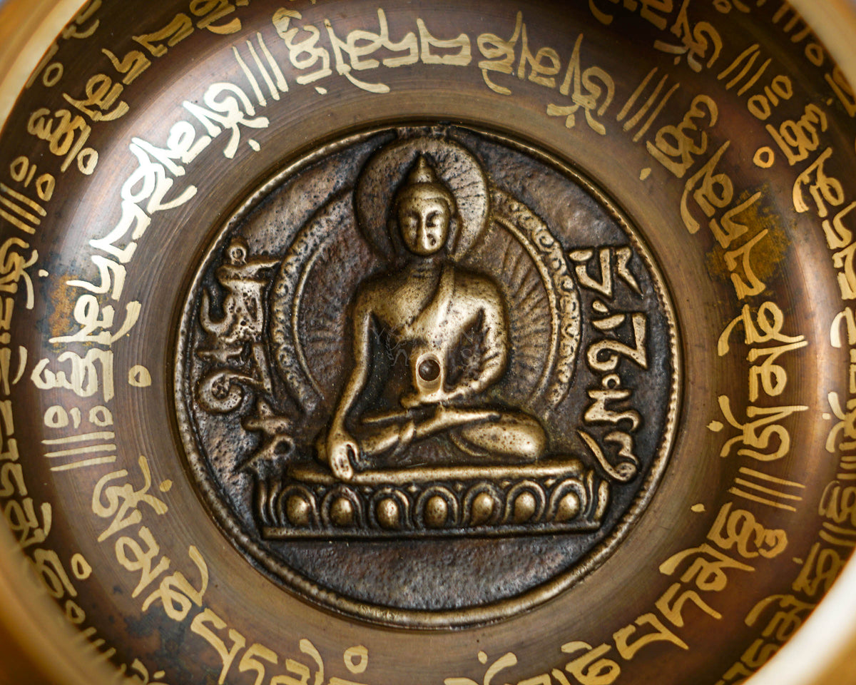 Close-up of seated Buddha relief inside handcrafted bronze singing bowl