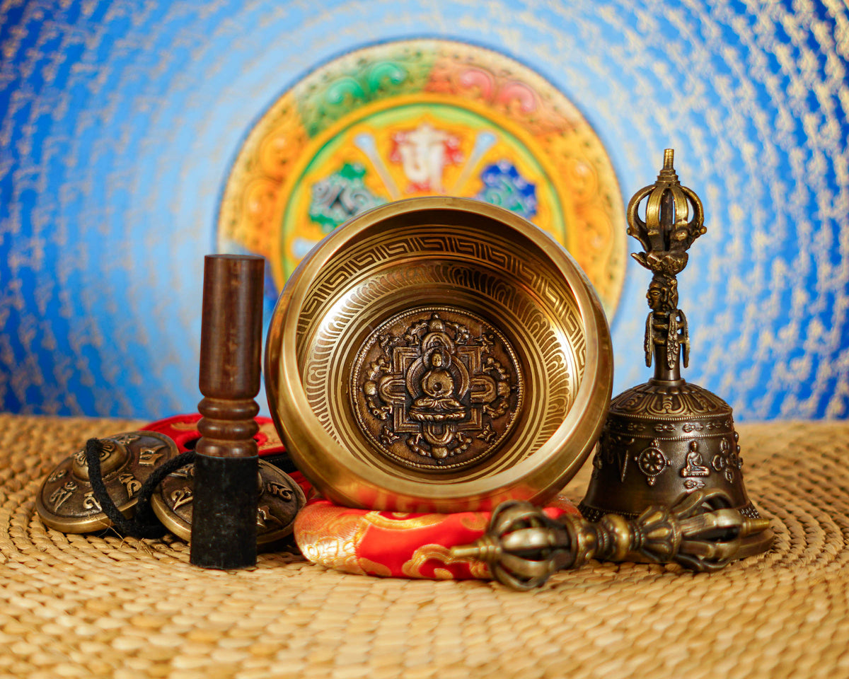 Handcrafted bronze Buddha singing bowl displayed with Buddhist ritual accessories