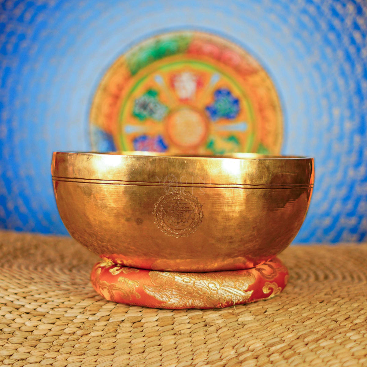 Chengresi Tibetan singing bowl with engraved Buddhist design on red cushion
