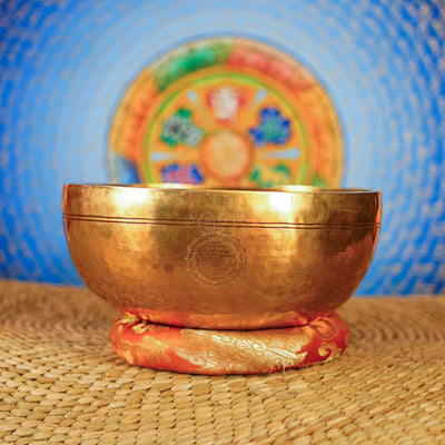 Chengresi Tibetan singing bowl with engraved Buddhist design on red cushion