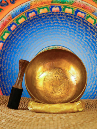 Medicine Buddha singing bowl with engraved Buddha design, yellow cushion and wooden mallet