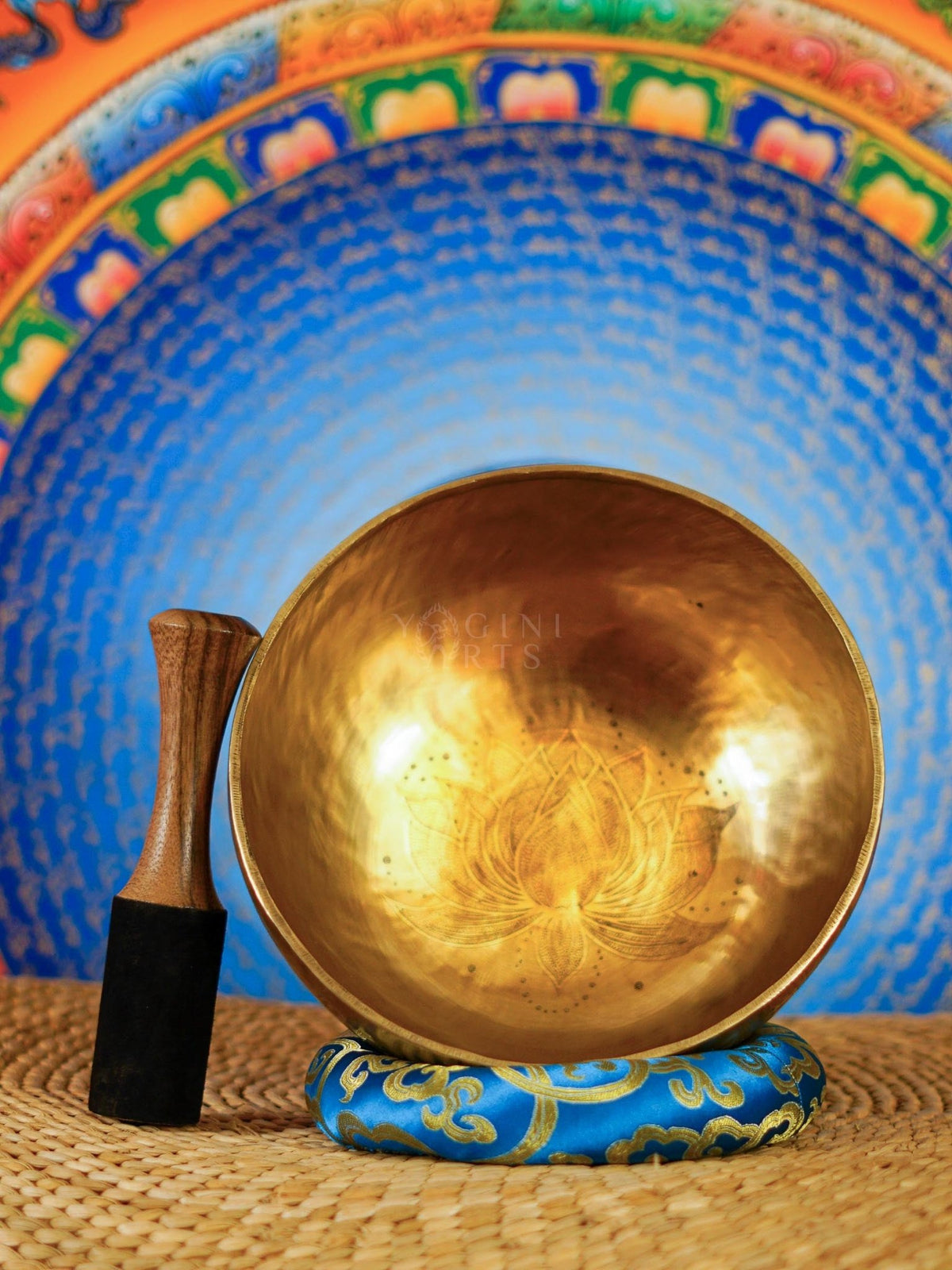 Handcrafted Tibetan singing bowl with engraved lotus flower design on the interior and blue decorative cushion