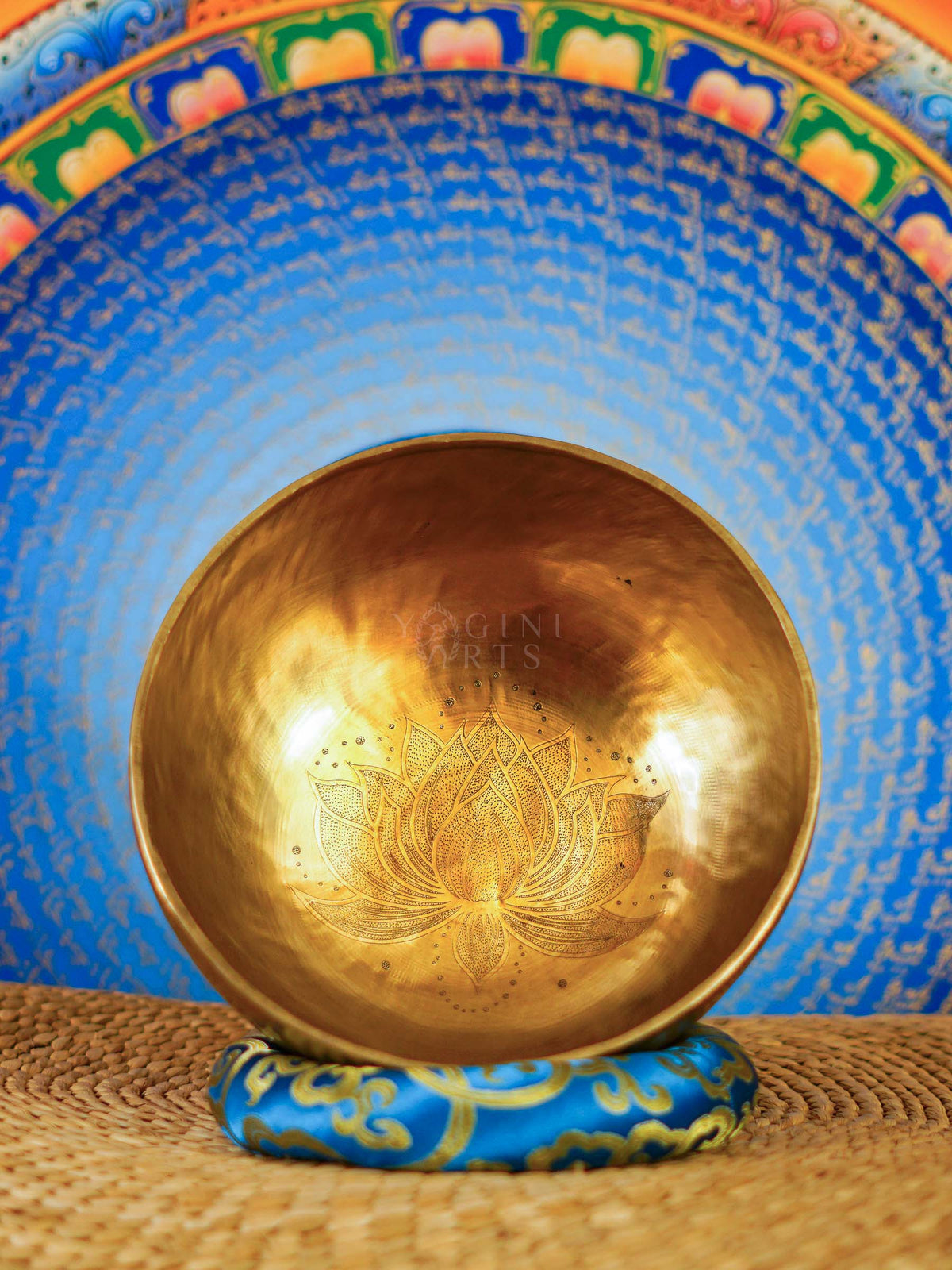Handcrafted Tibetan singing bowl with engraved lotus flower design on the interior and blue decorative cushion