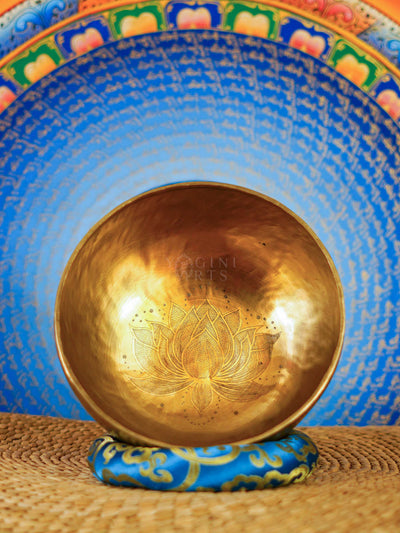 Handcrafted Tibetan singing bowl with engraved lotus flower design on the interior and blue decorative cushion