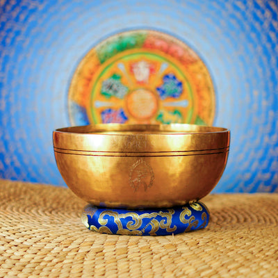 Kalchakra Mandala engraved Tibetan singing bowl shown on a blue decorative meditation cushion