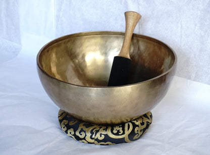 Handcrafted Tibetan brass singing bowl with wooden striker on brocade cushion
