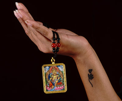 Hand-painted Zambala miniature Thangka pendant inside gold-accented copper Ghau locket with black and red beaded cord.