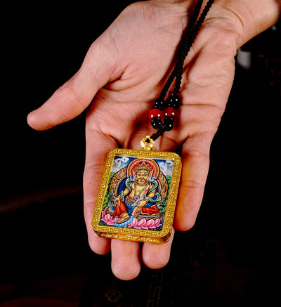 Hand-painted Zambala miniature Thangka pendant inside gold-accented copper Ghau locket with black and red beaded cord.