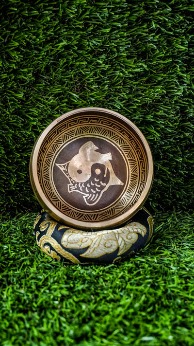 Yin Yang Fish Singing Bowl featuring two koi fish symbolizing balance and harmony. Wrapped in Om Mani Padme Hum mantra, it produces calming tones ideal for meditation and grounding.