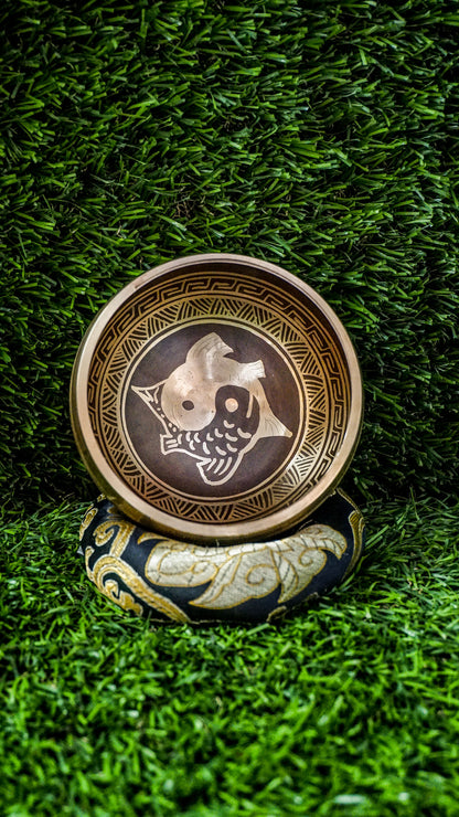 The Yin Yang Fish Singing Bowl celebrates balance and flow. Two koi fish swim in a yin yang pattern at its center, symbolizing harmony and life’s cycles. The Om Mani Padme Hum mantra wraps the outside, adding calming spiritual energy. Its clear, soothing tones help quiet the mind and bring focus. Perfect for meditation or creating peace, this bowl supports grounding and balance throughout your day