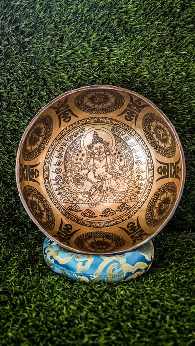 The Zambala Singing Bowl features Zambala, the deity of wealth and abundance, at its center with a radiant flower mandala. The outside is decorated with detailed mini mandalas and the Om Mani Padme Hum mantra, promoting prosperity and compassion. It produces rich, uplifting tones that support manifestation and spiritual grounding.