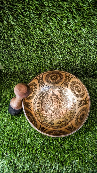 The Zambala Singing Bowl features Zambala, the deity of wealth and abundance, at its center with a radiant flower mandala. The outside is decorated with detailed mini mandalas and the Om Mani Padme Hum mantra, promoting prosperity and compassion. It produces rich, uplifting tones that support manifestation and spiritual grounding.