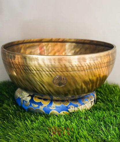 Brass singing bowl with a decorative base on grass