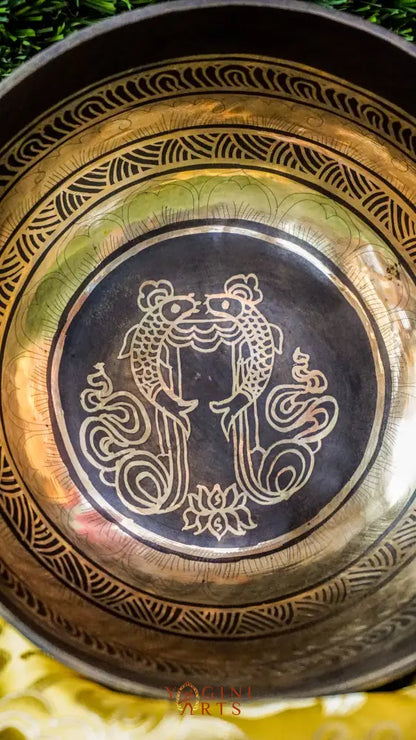 The Two Fish and Lotus Singing Bowl symbolizes harmony and growth. Inside, two fish face each other with a lotus beneath. The outside shows the Om Mani Padme Hum mantra in Tibetan. Its clear, calming tones support meditation and relaxation. Perfect for creating peace and balance in any space.