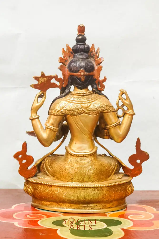Gold-plated statue of Chengresi (Chenrezig), the Tibetan Buddhist deity of compassion, depicted with four arms in a meditative posture, adorned with ornate jewelry and a serene facial expression.